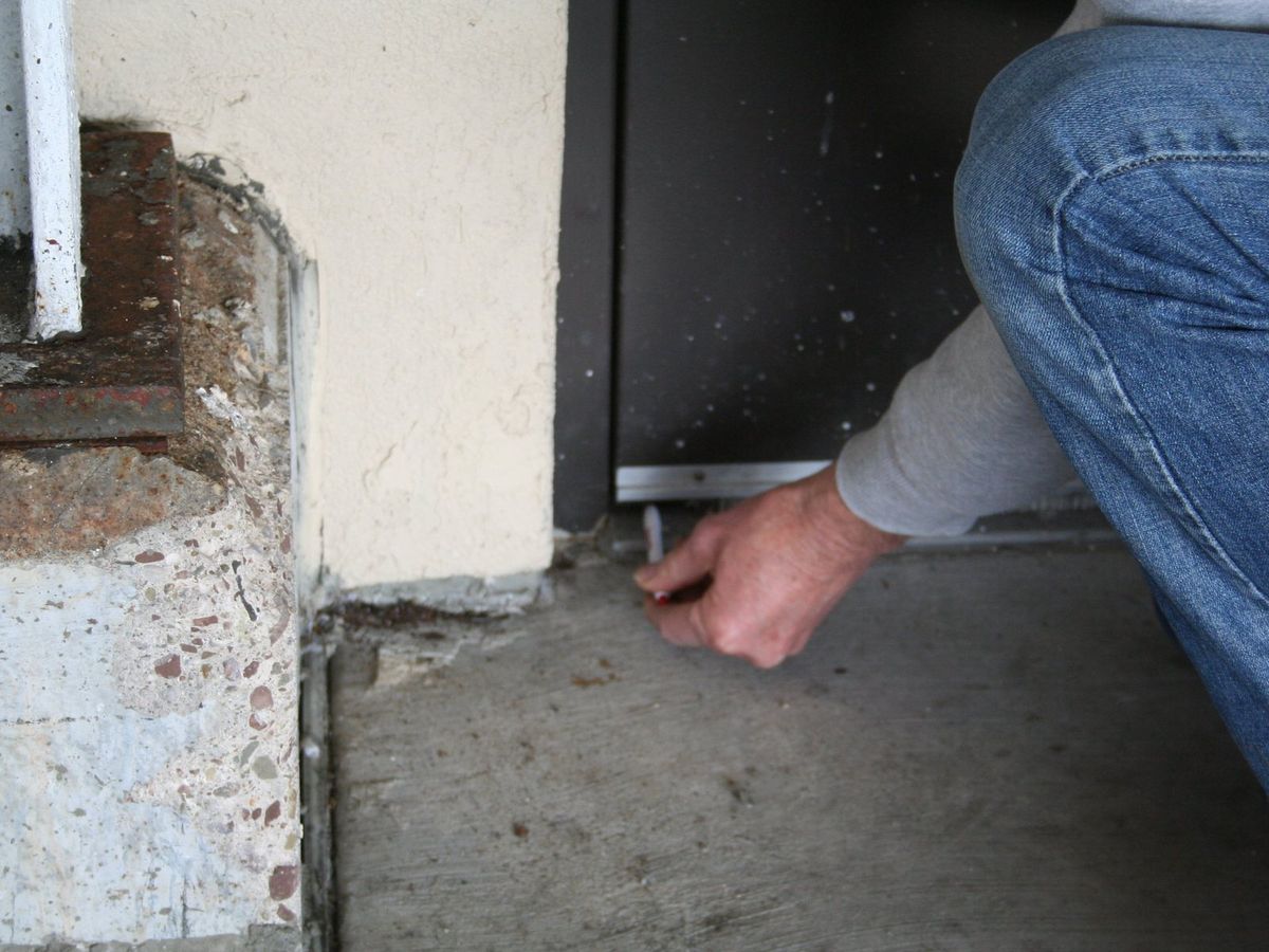 A hand checking the gap at the bottom of an exterior door